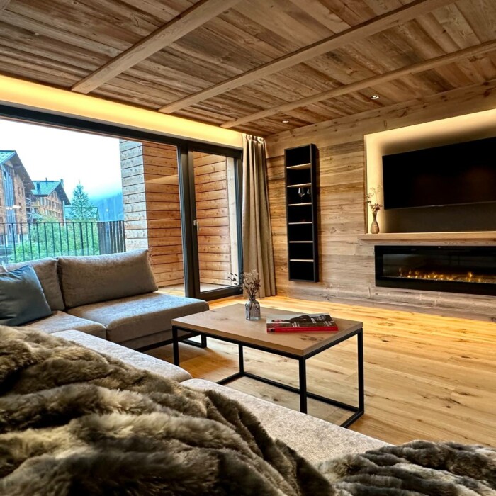 Luxus-Lodge am Arlberg mieten - NEU für 6 - 9 Personen - Wohnzimmer mit TV und Kamin, großer Balkon - Lech Valley Lodge