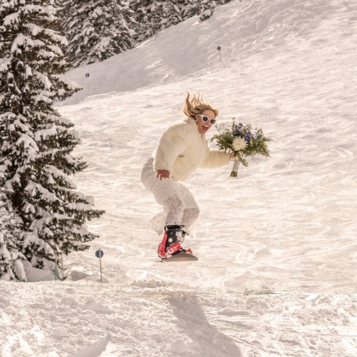 Hochzeit feiern in den Bergen am Arlberg – Braut auf Snowboard im Skigebiet Ski Arlberg in Österreich